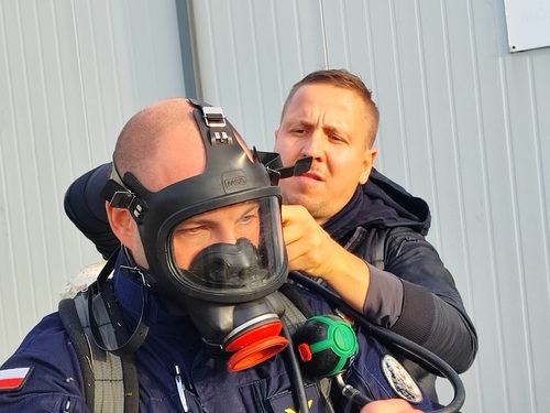 Funkcjonariusz SG w trakcie zakładania maski oddechowej Funkcjonariusz SG w trakcie zakładania maski oddechowej