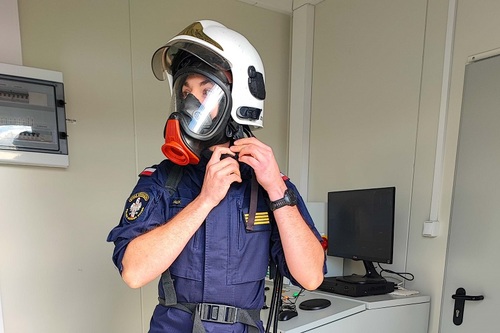 Funkcjonariusz SG zakłada hełm ochronny oraz maskę oddechową Funkcjonariusz SG zakłada hełm ochronny oraz maskę oddechową
