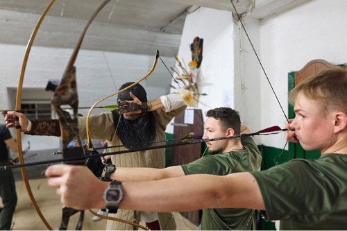 Studenci WSSG trzymają w rękach łuk. W tle widać instruktora KKR w historycznym stroju. Studenci WSSG trzymają w rękach łuk. W tle widać instruktora KKR w historycznym stroju.